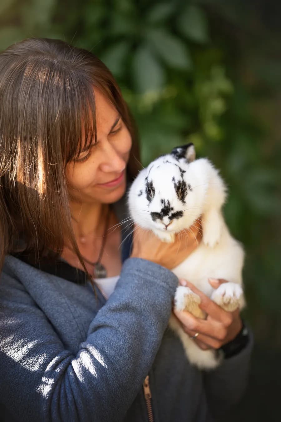 Katharina hält ein weiß-schwarz geschecktes Kaninchen im Arm